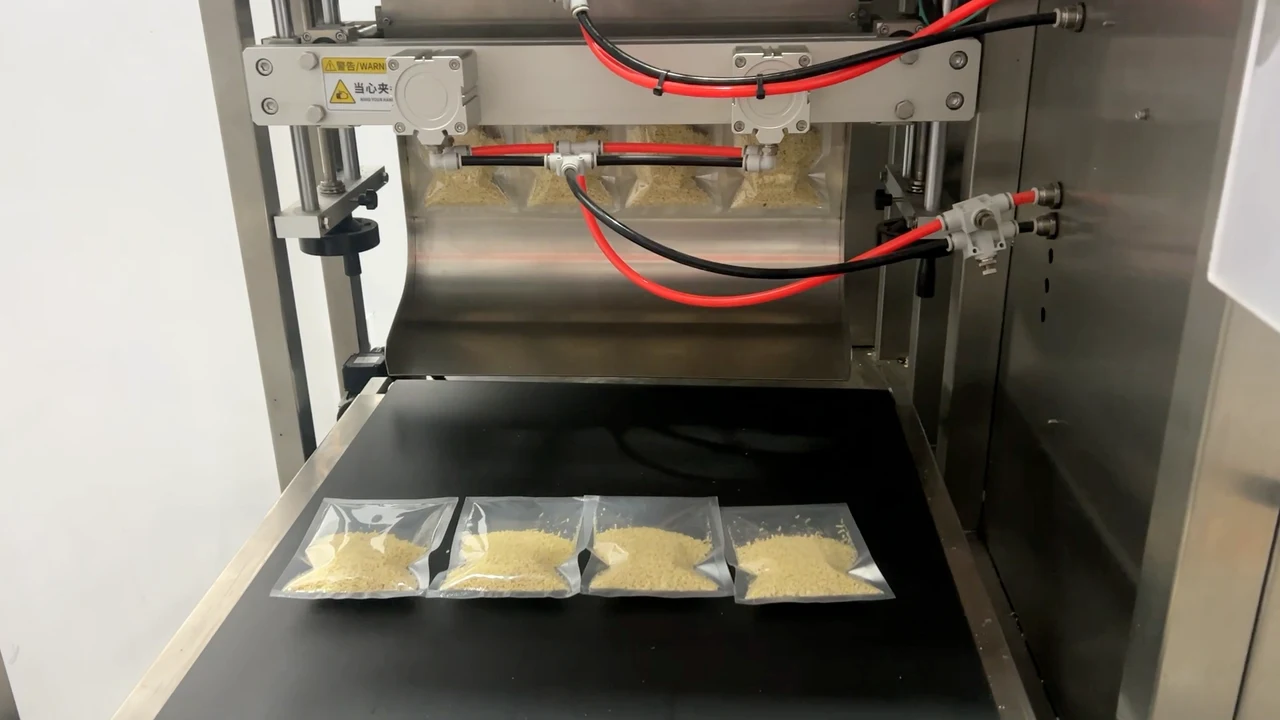 Four transparent sachets containing visible granules on the conveyor below the machine discharge.